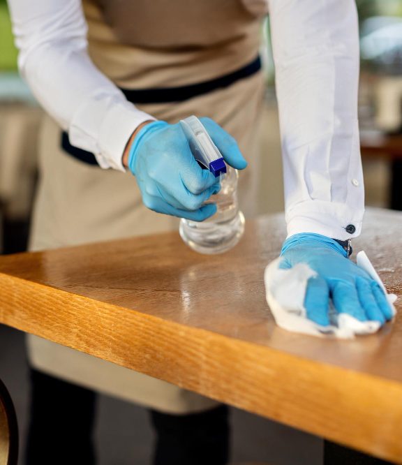 closeup waiter disinfecting cafe tables after work e1712088266191